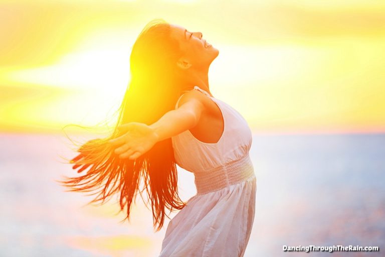 A woman standing in the sun with her arms open wide