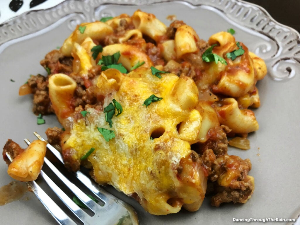 A scoop of Cheesy Beefaroni Casserole on a plate with a metal fork