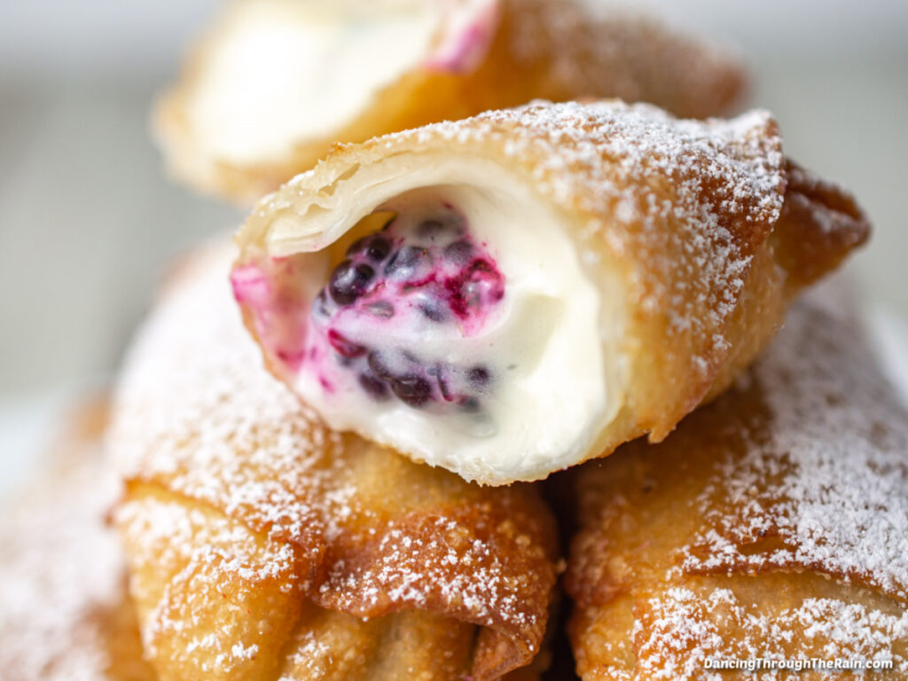 A closeup of the inside of a Blackberry Cheesecake Egg Roll with two others underneath it