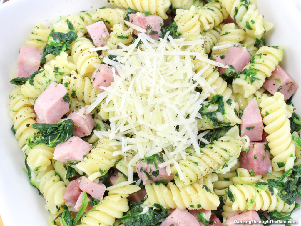 A closeup of Ham, Spinach, and Cheese Pasta in a white frying pan